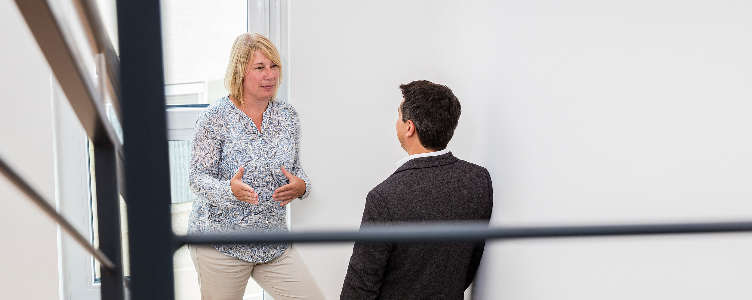 Mitarbeiterin unterhält sich mit Kunden im Flur der der Steuerkanzlei SWRP